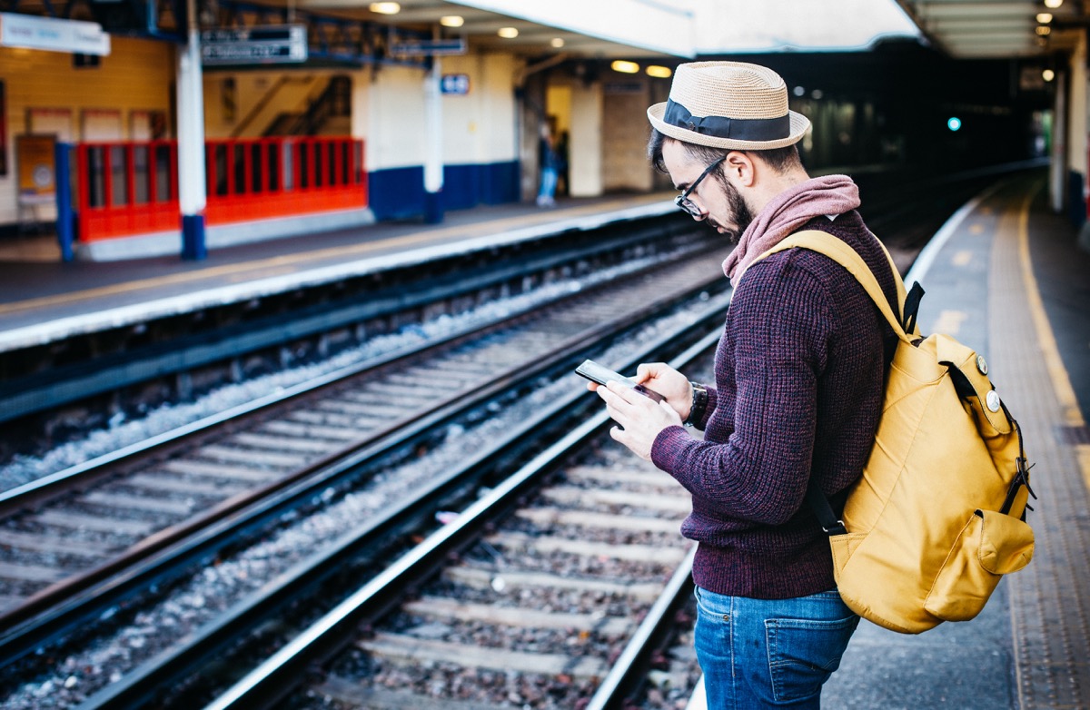 man commuting, looking at smartphone; representing the importance of a localized web presence